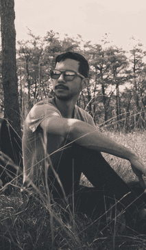 Image of Jean Carlos sitting down next to a tree