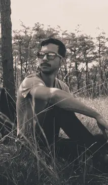 Image of Jean Carlos sitting down next to a tree